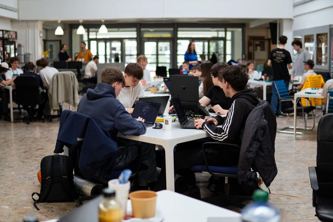 Tím pri spoločnom stole s laptopmi na hackathone